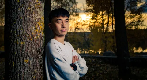 LUT University student leaning to a tree in a sunset