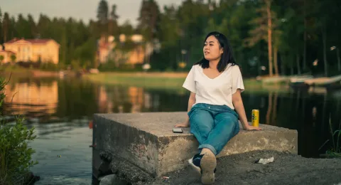 LUT University master&#039;s student sitting on a concrete block at the shore