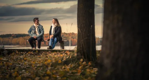 LUT University students sitting on a bench at sunset