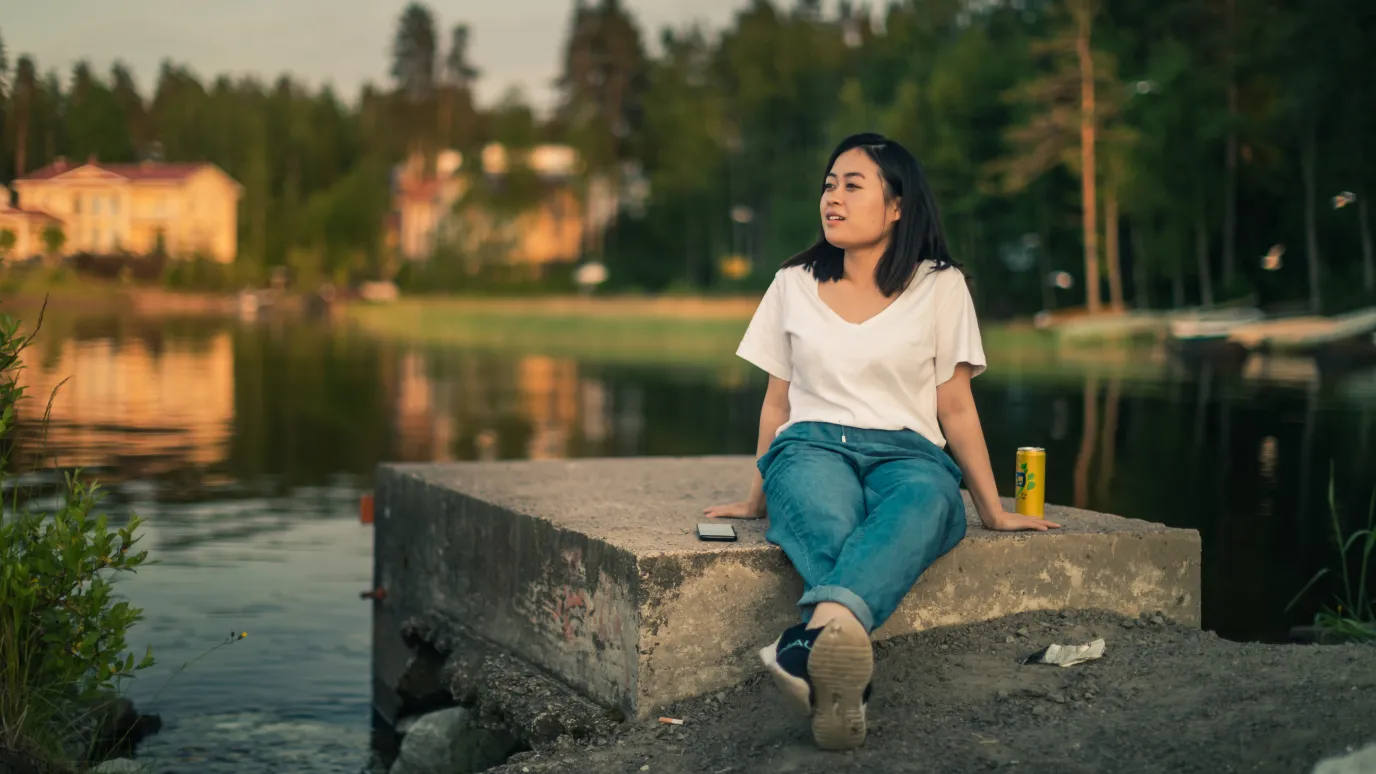 LUT University master's student sitting on a concrete block at the shore