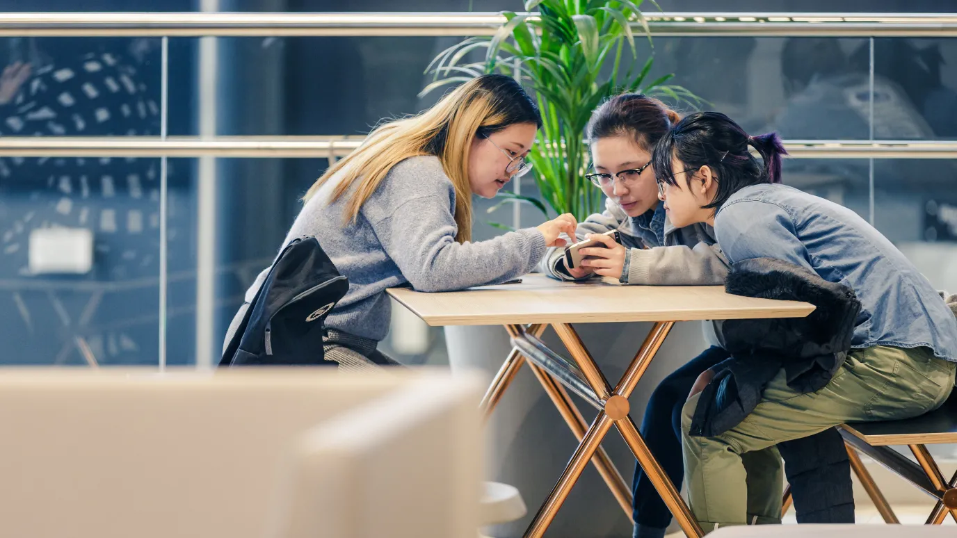 LUT students checking phone in campus cafeteria.